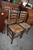 A set of four oak rush seated ladderback chairs. Seat heights, 45CM. Some damages to rush seating.