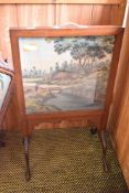 An Edwardian mahogany firescreen, inset with painted silk Oriental rural scene raised on slender