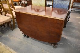 A 1940s mahogany dropleaf dining table with turned supports and rounded flaps, 74CM. X. 105CM.