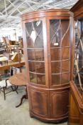 A reproduction bow fronted mahogany corner cupboard, with glazed upper doors. 206 CM.