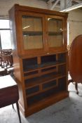 A Victorian light oak bookcase, having a moulded surmount over two glazed cupboard doors, the