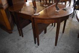 An early 20th century mahogany D end dining table with central dropleaf section, all raised on