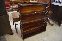 An early 20th century simulated Rosewood waterfall bookcase, with fret cut and stepped ends.