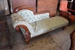 A late Victorian mahogany show frame chaise longue, having a deep buttoned scrolled arm and shaped