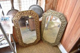 Two early 20th century embossed brass mounted bevelled mirrors, of canted rectangular form.