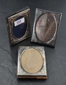 A group of three small silver mounted photograph frames, each of rectangular form with oval aperture