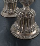 A pair of Tibetan white metal butter lamps, having flared cylindrical bowls with moulded