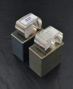 A pair of 1930's silver napkin rings, each of rectangular form with curved ends and engine-turned