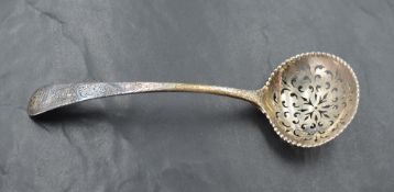 An 18th century silver sifting spoon, the circular bowl with bead moulded rim enclosing the