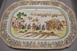 A large Chinese porcelain charger decorated with scenes of Oriental merchants at dock side in a