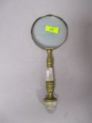 A brass framed antique magnifying glass having mother of pear inlay to handle.