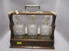 An early 20th century oak Tantalus having white metal handle and brackets to top and sides.