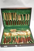 A mid century cutlery canteen having brass and teak handles