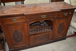 A Victorian side board or dresser base in mahogany with carved doors, triple drawers and cupboards