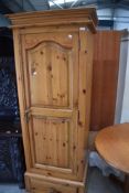 A modern pine single wardrobe or hallrobe of deep proportions having drawer base