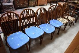 A set of five dark oak wheel back dining chairs with an additional carver chair