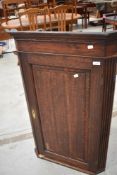 A 19th Century oak corner cupboard having brass escutcheon