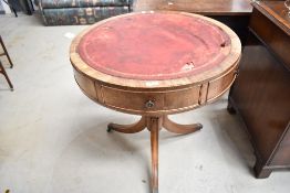 An early 20th century drum table with three drawers and red leather top on tripod pedestal base