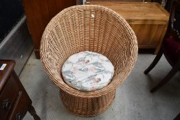 A mid century style woven wicker tub chair