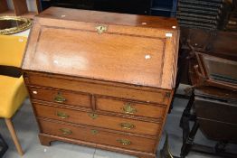 A Georgian golden oak bureau having brass handles and bracket feet