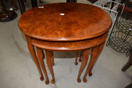 A modern yew wood nest of three tables having cabriole legs