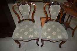 A pair of Victorian mahogany salon chairs having scroll frames overstuffed seats and backs