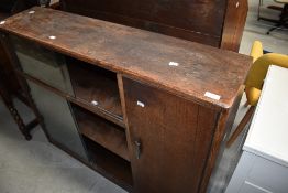 An early 20th Century oak bookcase with sliding glass doors and cupboard to side