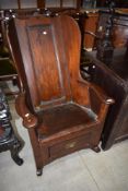 An 18th Century and later dark stained pine Vernacular lambing rocking armchair with solid back