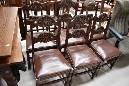 A set of five dark oak dining chairs with an additional carver chair having carved double backs