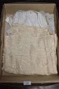 An early 20th century christening shawl having embroidered details with a similar shawl and apron