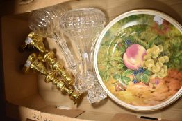 Two vintage decanters, two plates having fruit designs and a pair of brass candlesticks.