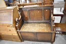 A traditional oak box settle having lion arms