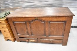 An 18th century oak mule chest, having a planked rectangular top over three fielded panels and two
