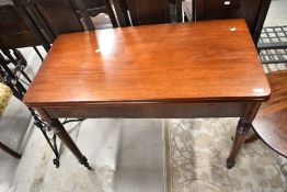 A Victorian mahogany fold over tea table having turned legs and brass castors
