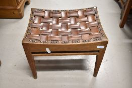 An Arts and Crafts oak and leather stool in the Simpson Handicrafts or Stanley Webb Davies style