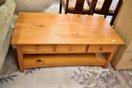 A modern part pine coffee table having three drawers and undershelf, matches lot 572