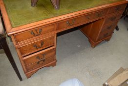 A reproduction yew wood pedestal desk having skiver leather desk top