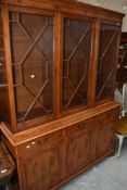 A reproduction yew wood bookcase having astral glazed display section over triple drawer and