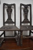 A pair of period oak hall chairs having carved sheep or goat head decoration (satanic?) dated 1830