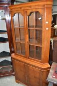 A reproduction yew wood corner display having cupboard under
