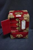 A 20th century Japanese style lacquer work case having brass details with stone carved door insets