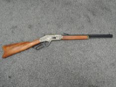 A Denix reproduction metal and wood Winchester Rifle having hexagonal barrel with hunting scene on