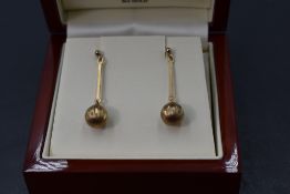 A pair of 9ct gold stud earrings having facetted diamond cut spheres on bar drops, approx 2.4g