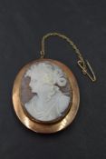A large conch shell cameo brooch depicting a Grecian maiden in a rose gold plain collared mount