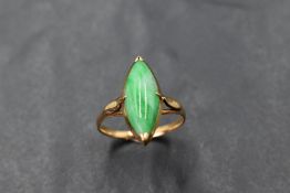 A yellow metal and jadeite ring, the marquise shaped green stone between slender shaped shoulders,