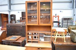 A vintage teak wall unit of narrow proportions with display and shelved section over double