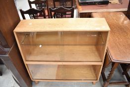 A vintage golden oak bookcase having sliding glass doors