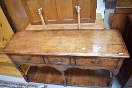 A reproduction dresser base in the period style having three frieze drawers, shaped apron with shelf