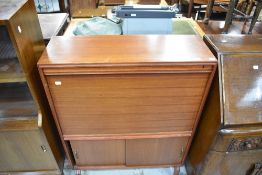 A 1970s teak bureau, with cupboards to base having sliding doors