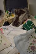 A vintage travel case containing a selection of embroidered table linen and similar.